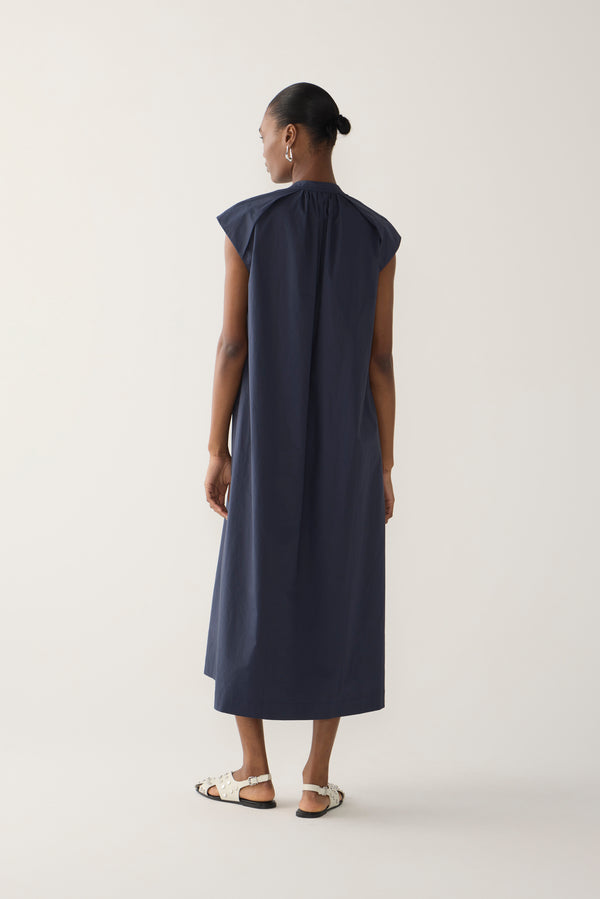 Woman wearing a navy sleeveless dress on a white background