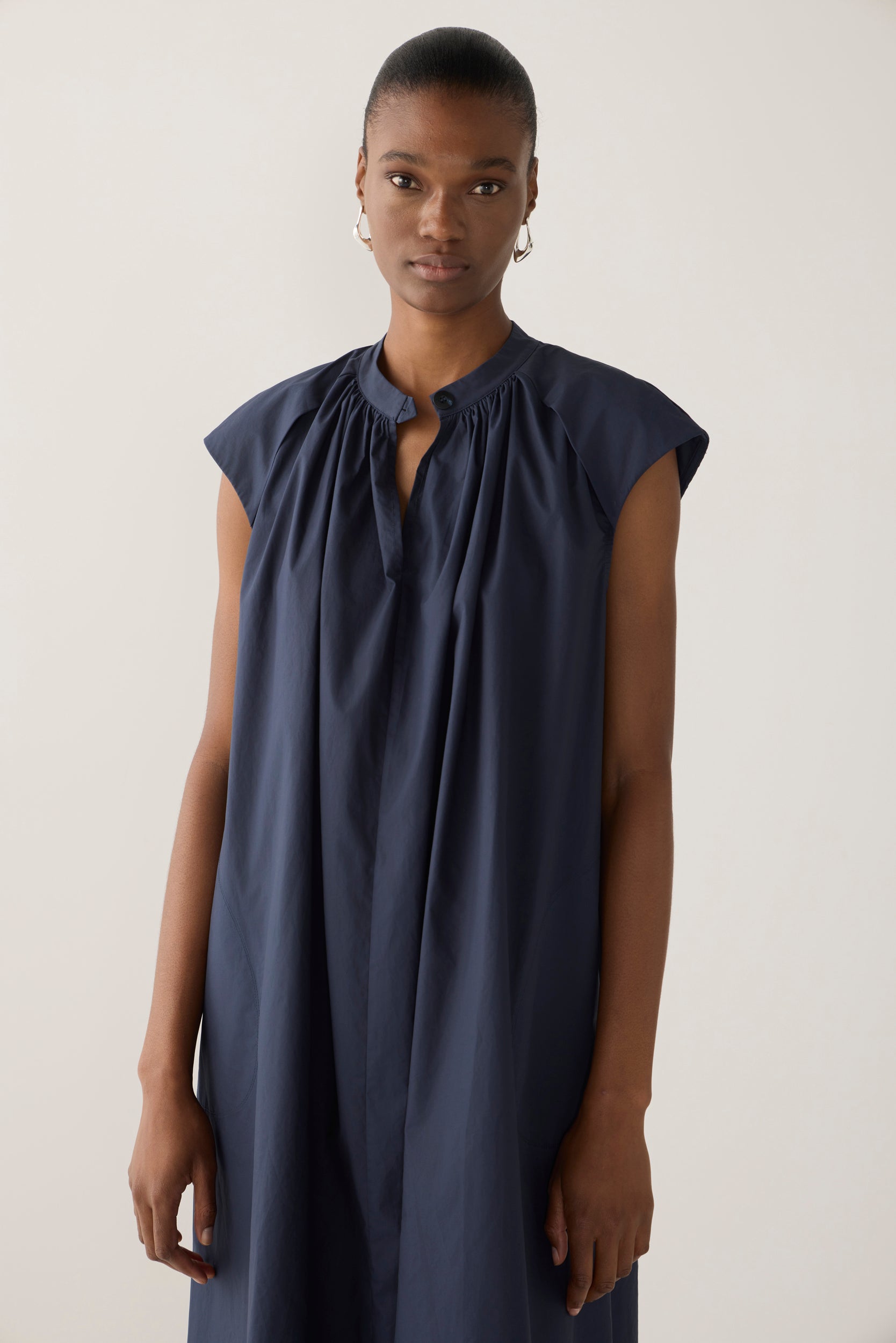 Woman wearing a navy sleeveless dress on a white background