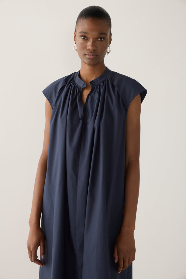 Woman wearing a navy sleeveless dress on a white background