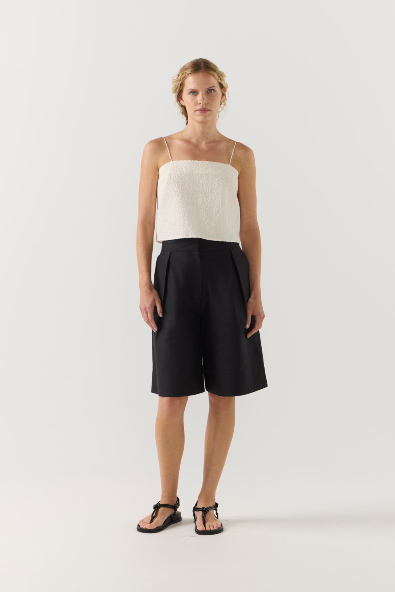 Woman wearing a white top and black shorts on a white background