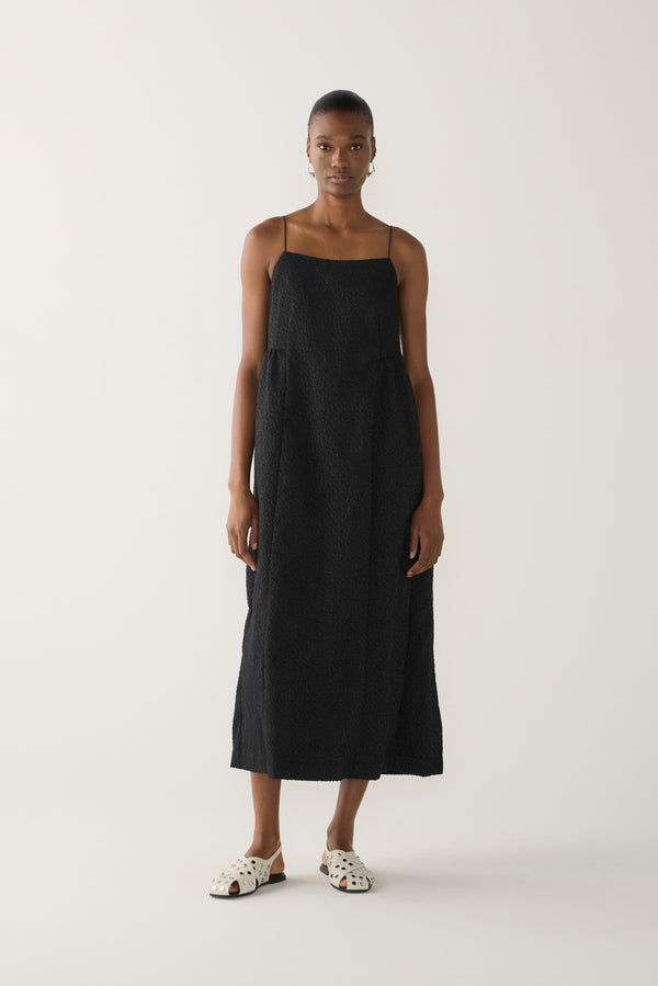 Woman wearing a black slip dress on a white background