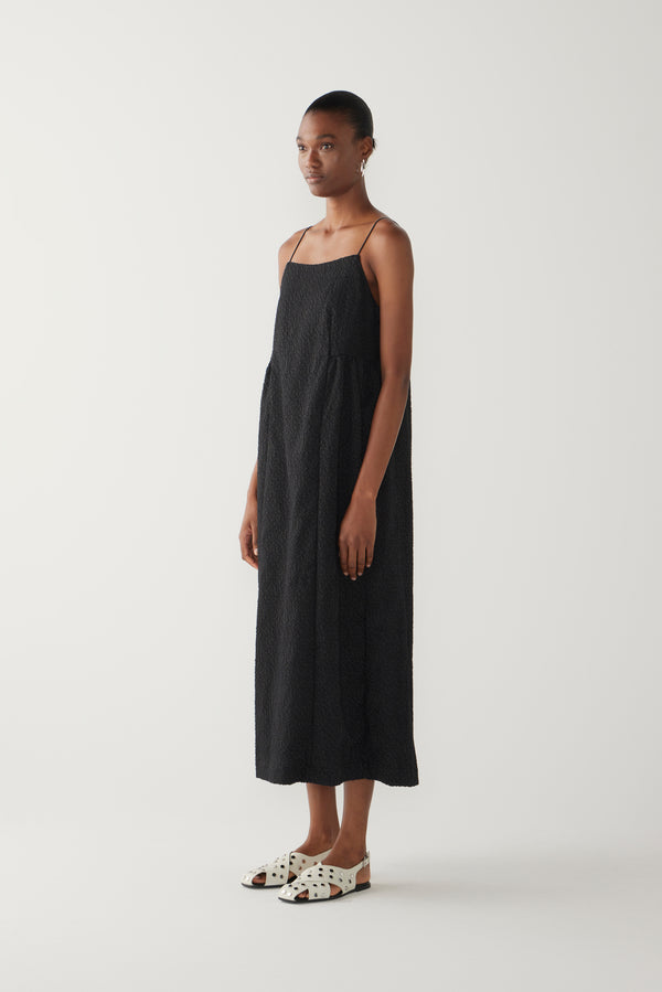 Woman wearing a black slip dress on a white background
