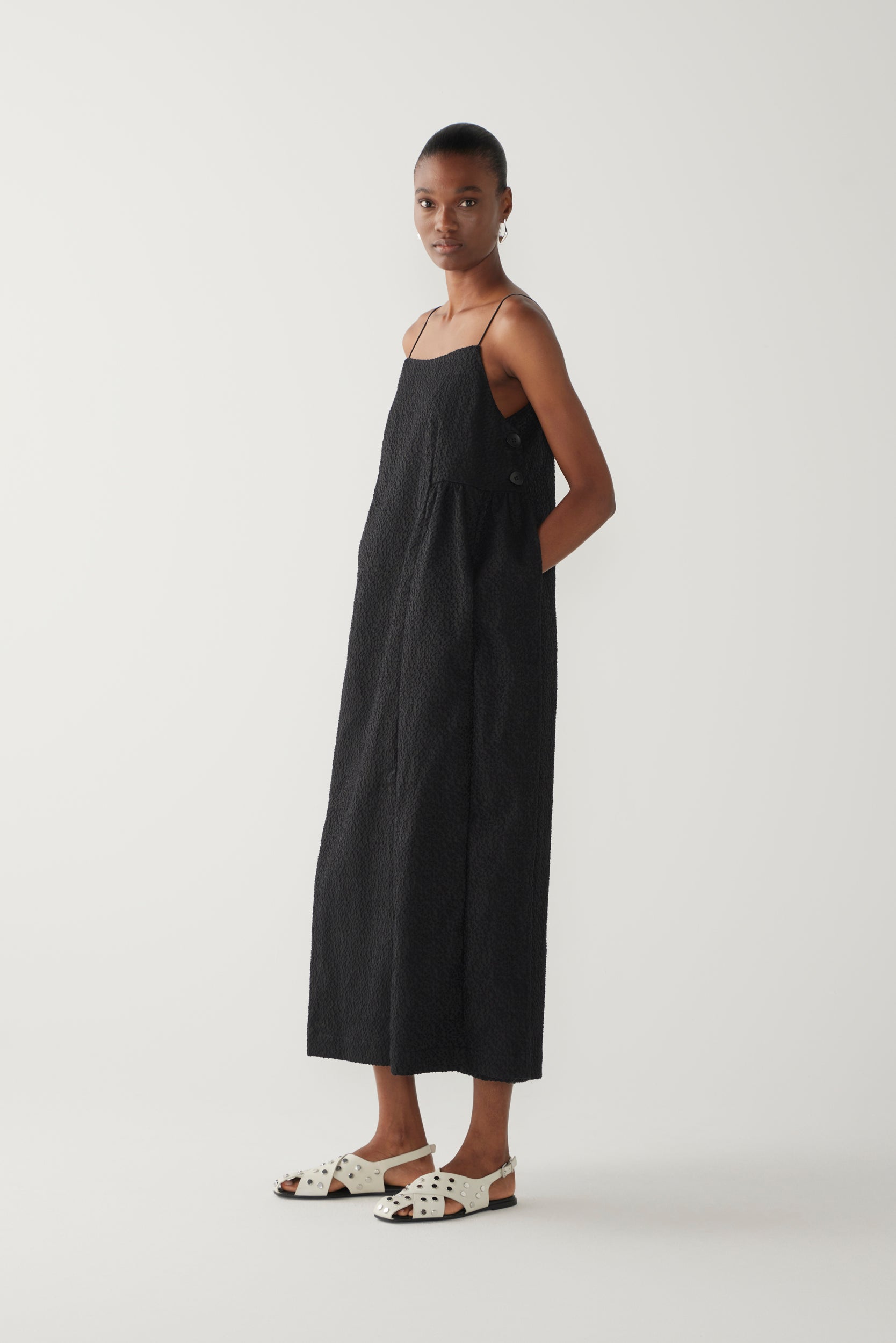 Woman wearing a black slip dress on a white background