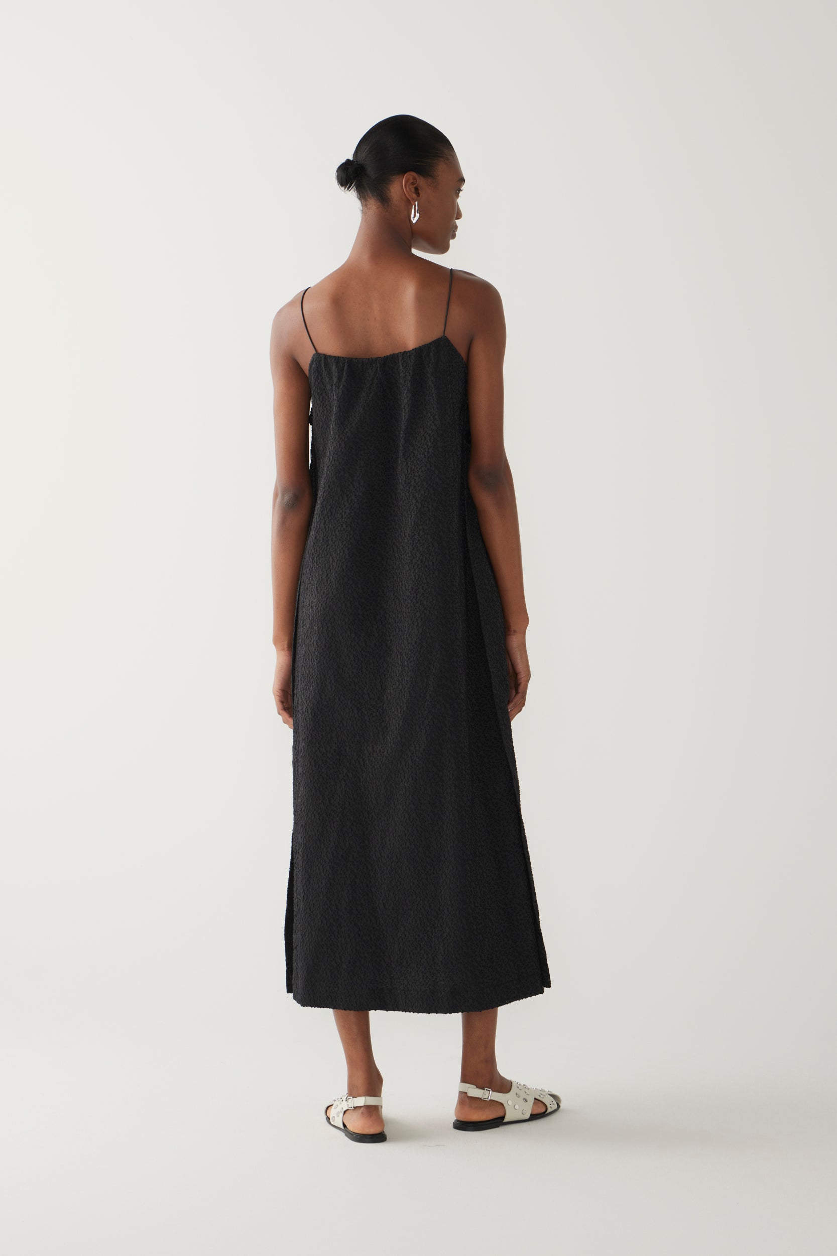 Woman wearing a black slip dress on a white background