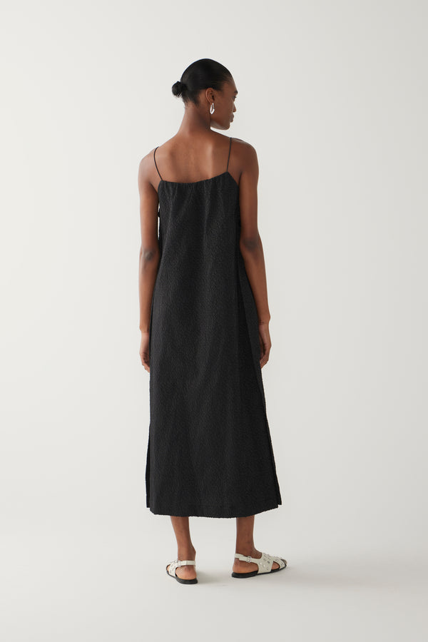 Woman wearing a black slip dress on a white background