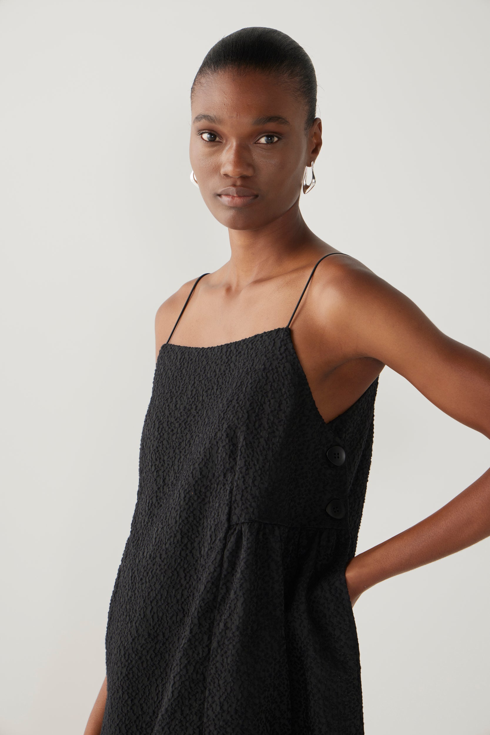 Woman wearing a black slip dress on a white background