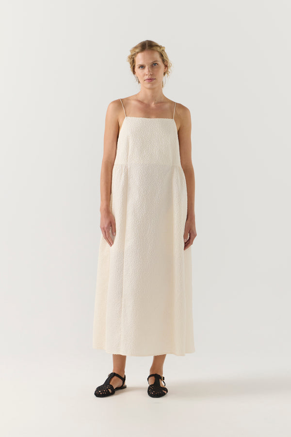 Woman wearing a white dress on a plain background