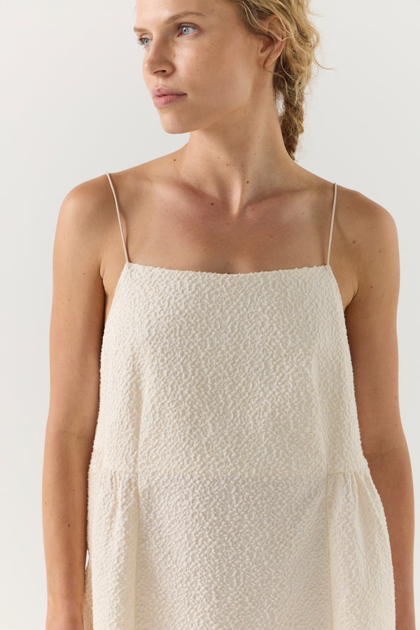 Woman wearing a white dress on a plain background