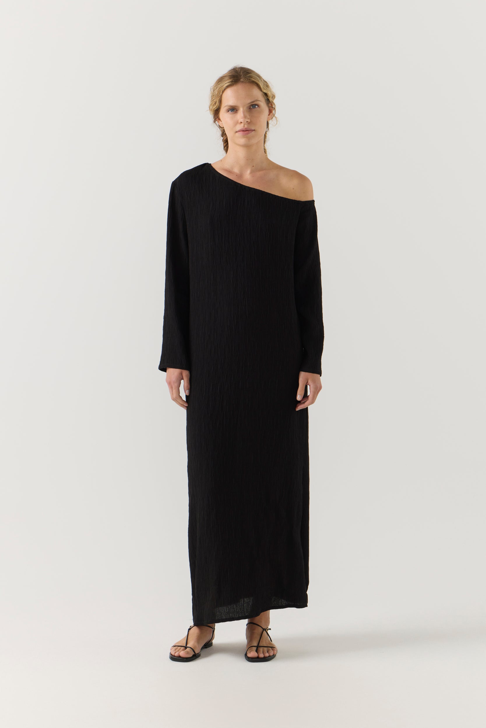 Woman wearing a black one-shoulder dress on a white background