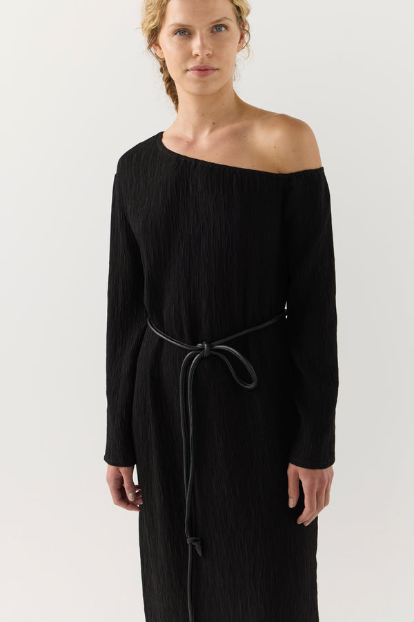Woman wearing a black one-shoulder dress on a white background