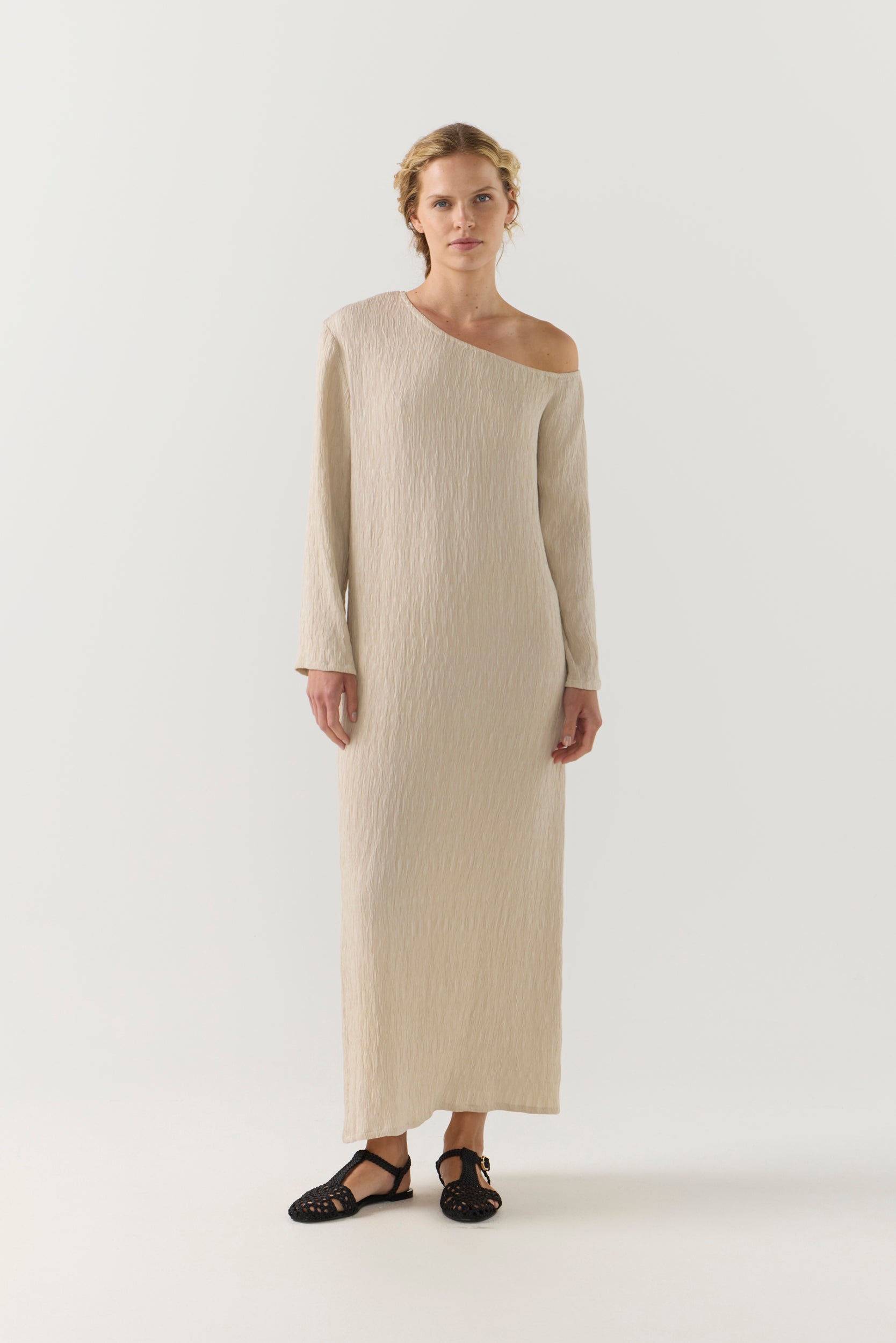 Woman wearing a beige one-shoulder dress on a white background