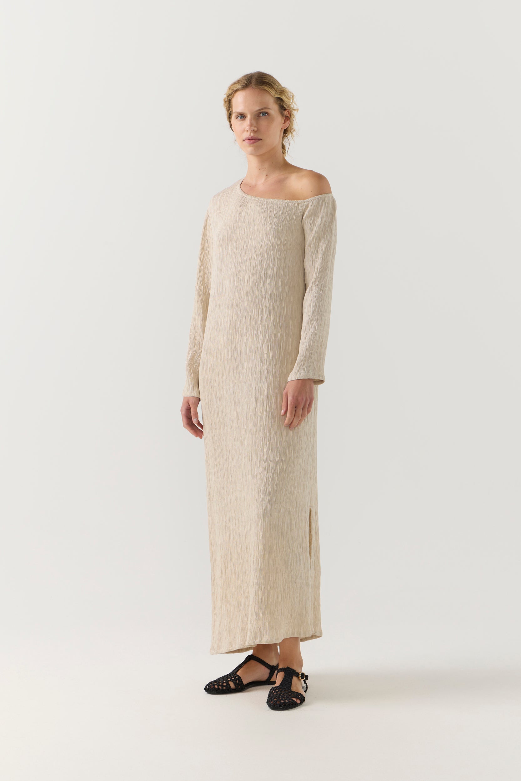 Woman wearing a beige one-shoulder dress on a white background
