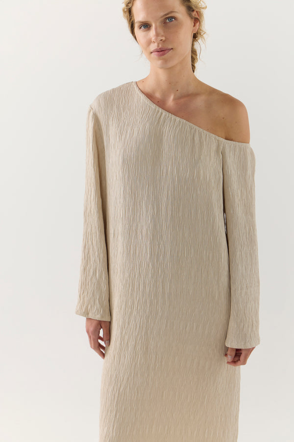 Woman wearing a beige one-shoulder dress on a white background