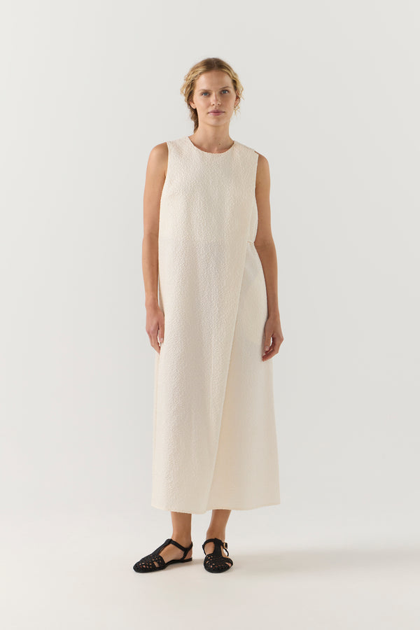 Woman wearing a white sleeveless dress on a plain background