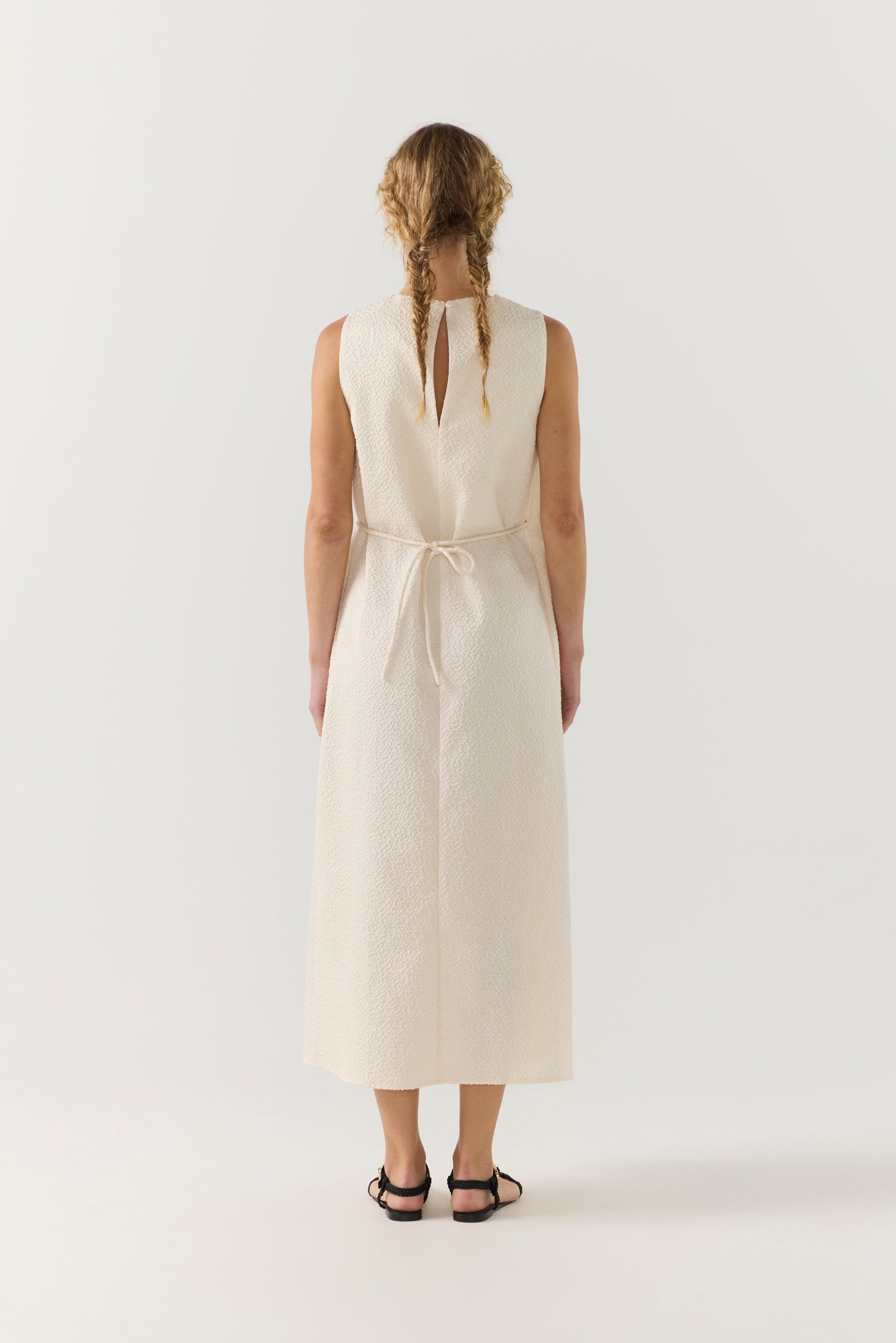 Woman wearing a white dress with a belt on a white background