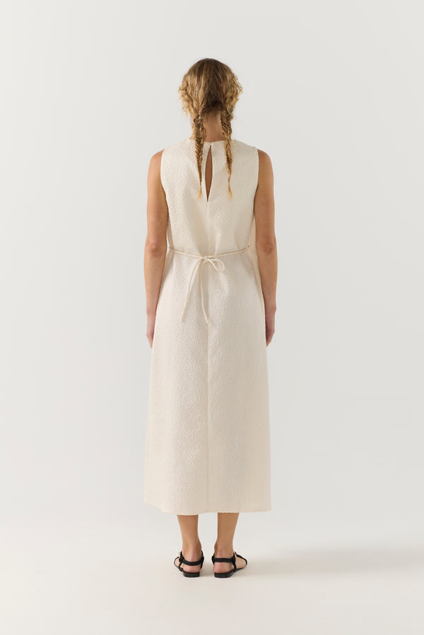 Woman wearing a white dress with a belt on a white background