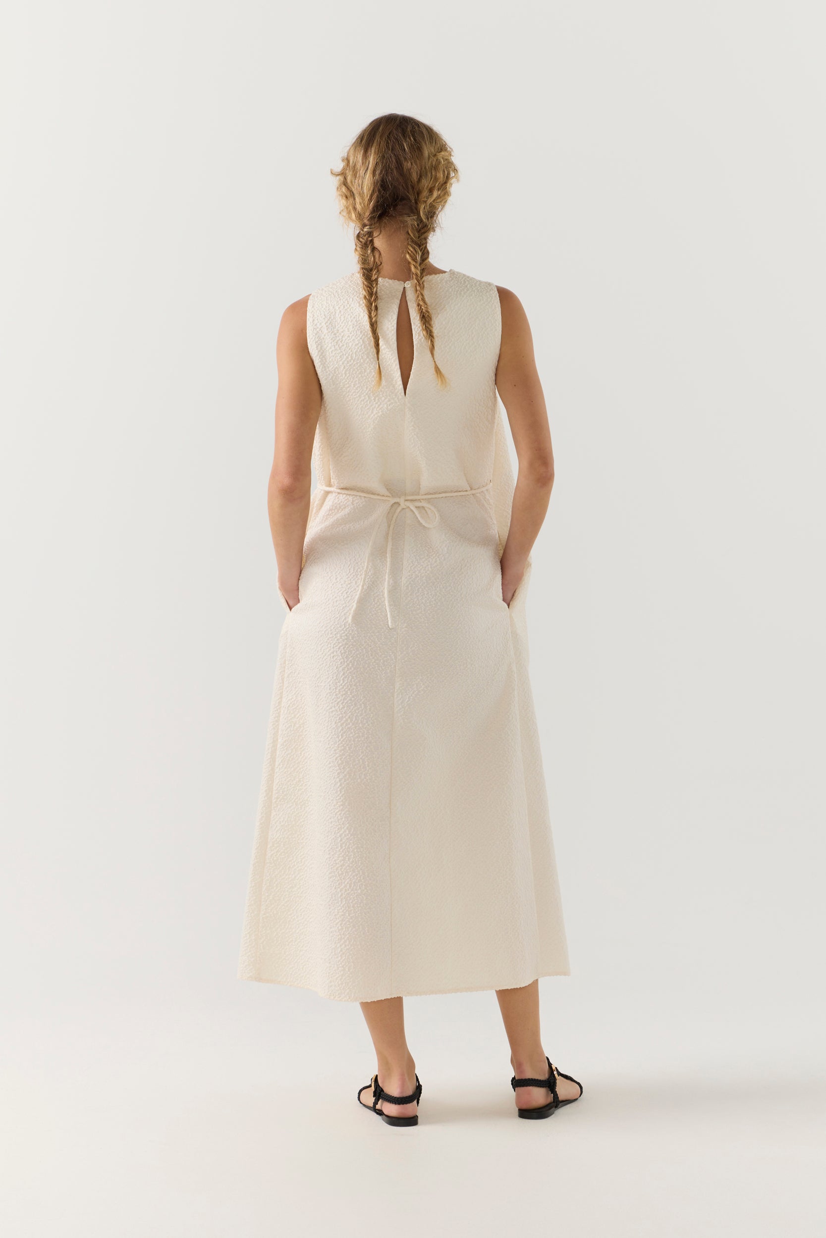 Woman wearing a white sleeveless dress on a plain background