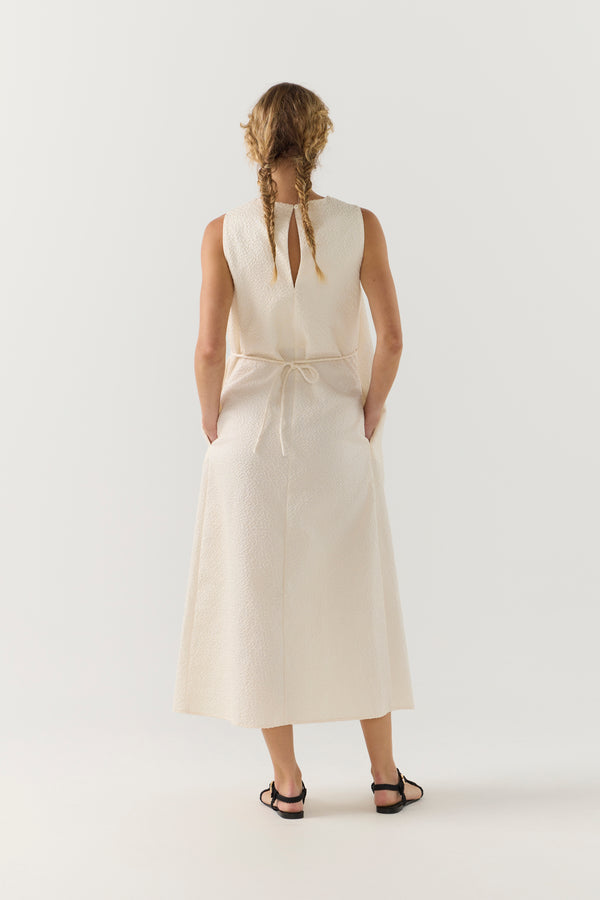 Woman wearing a white sleeveless dress on a plain background