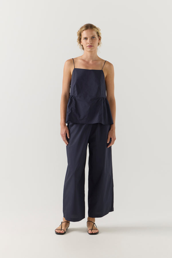 Woman wearing a navy blue singlet and pant on a white background