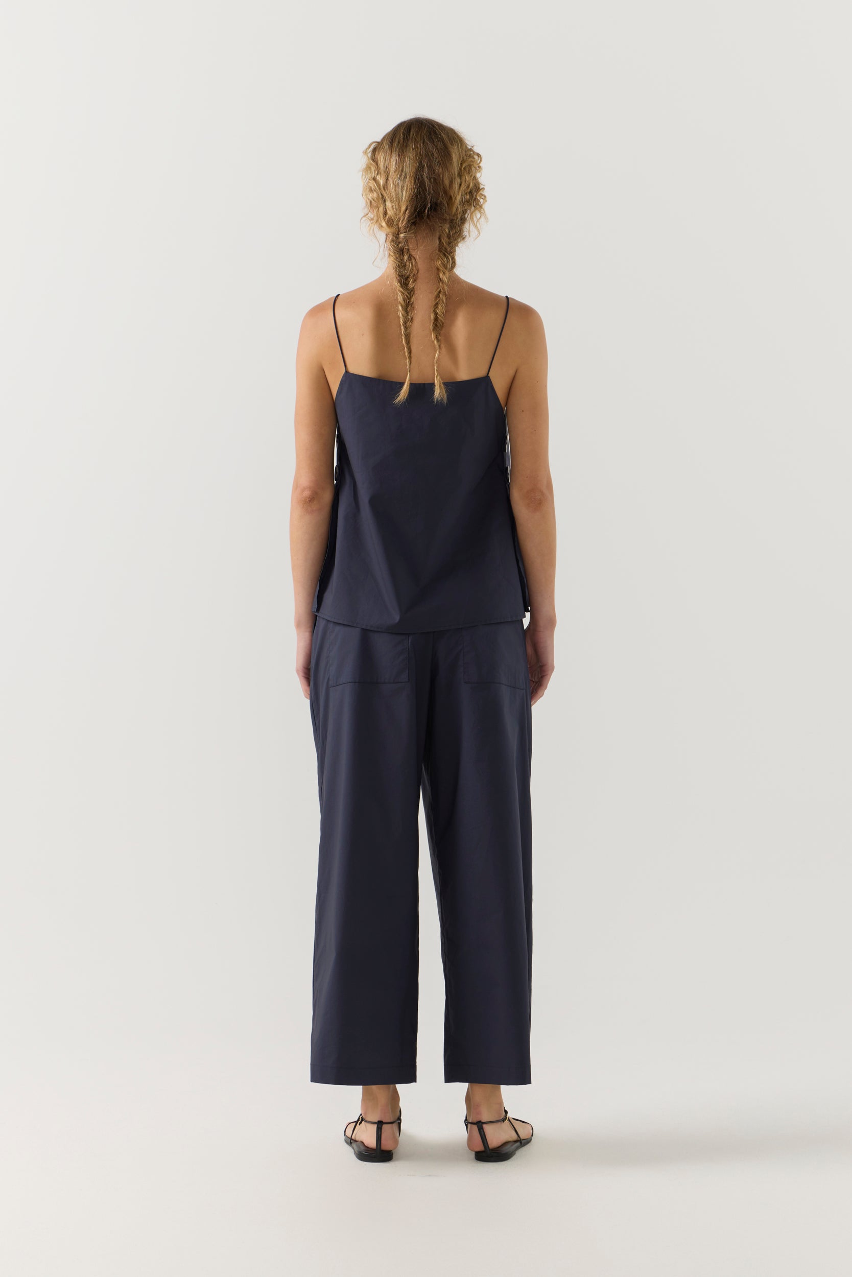 Woman wearing a navy blue singlet and pant on a white background