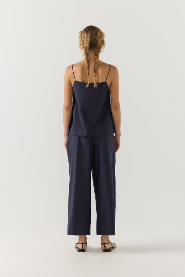 Woman wearing a navy blue singlet and pant on a white background
