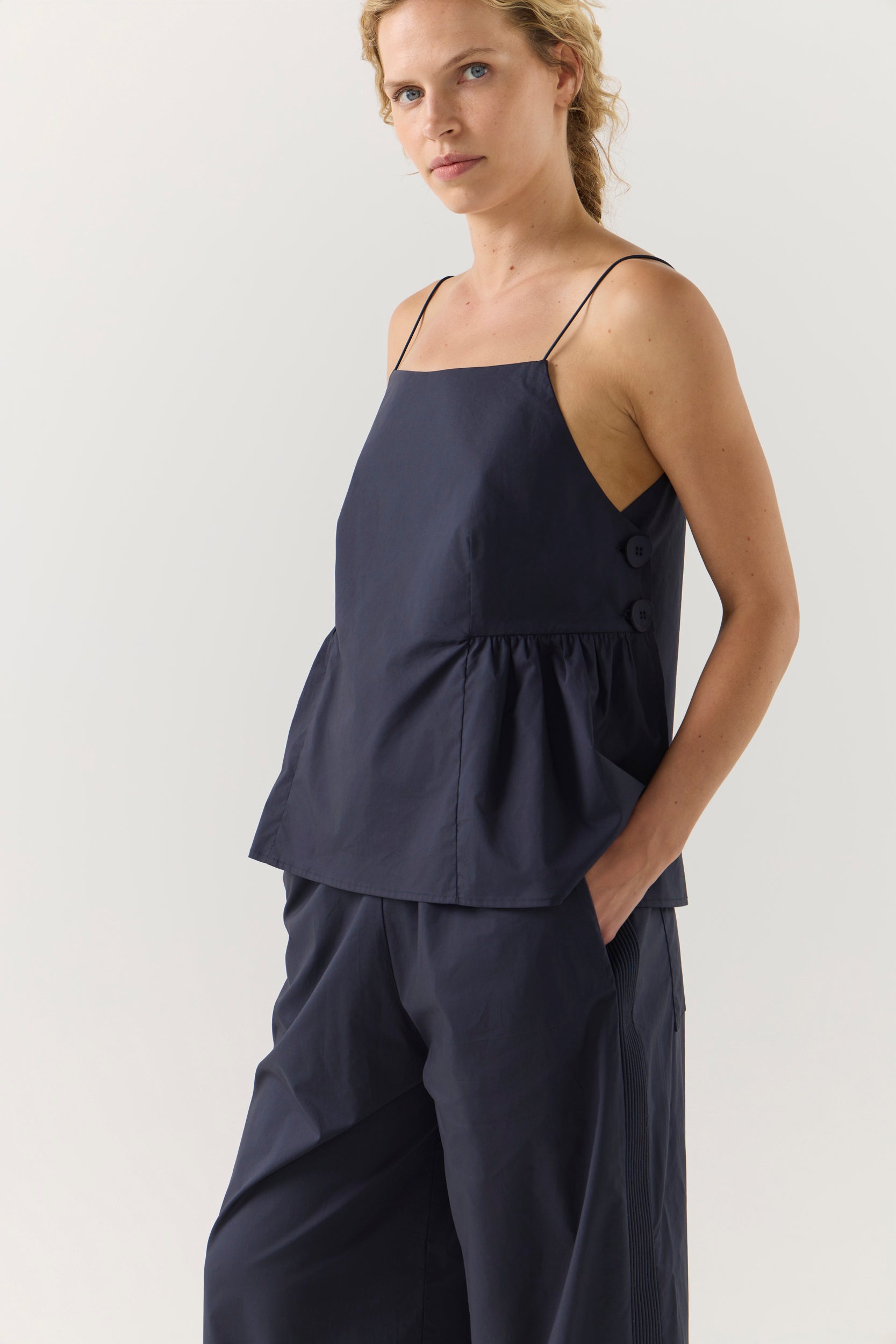 Woman wearing a navy blue singlet and pant on a white background