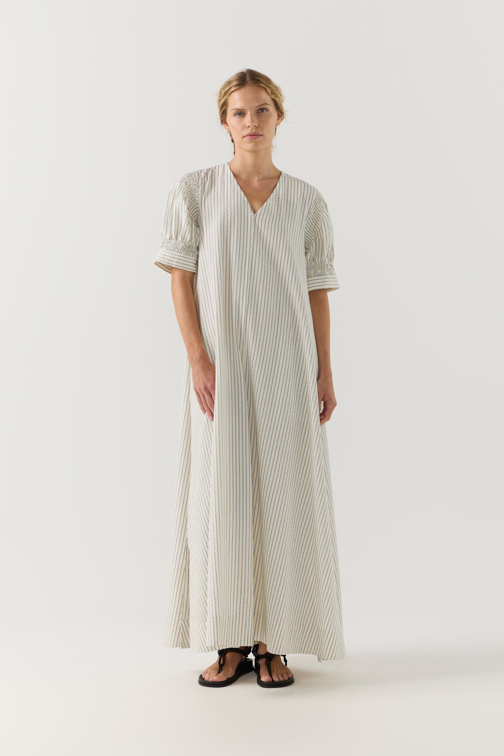 Woman wearing a white and green striped dress on a white background