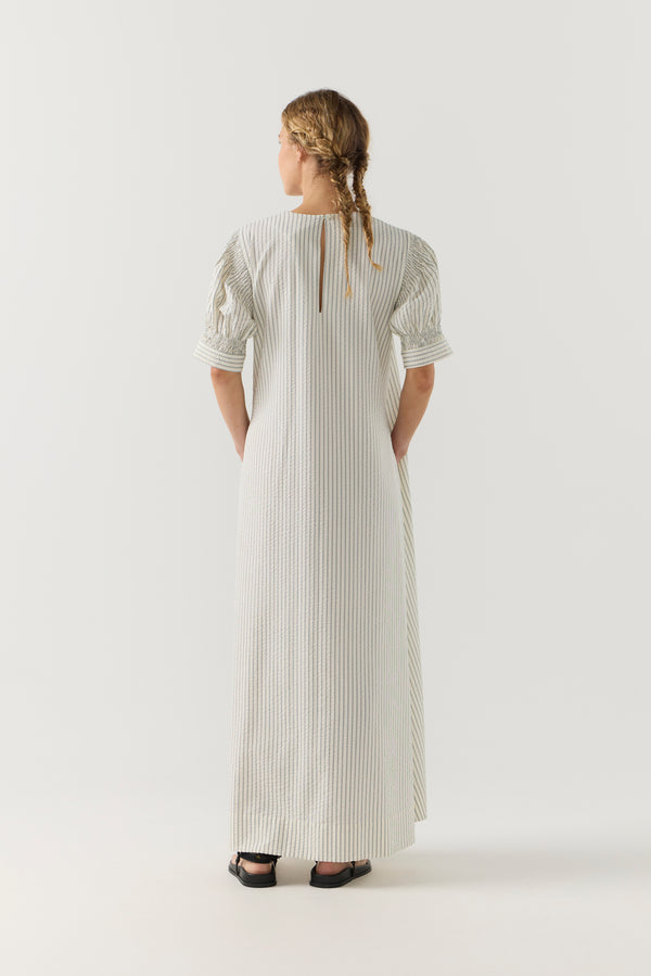 Woman wearing a white and green striped dress on a white background