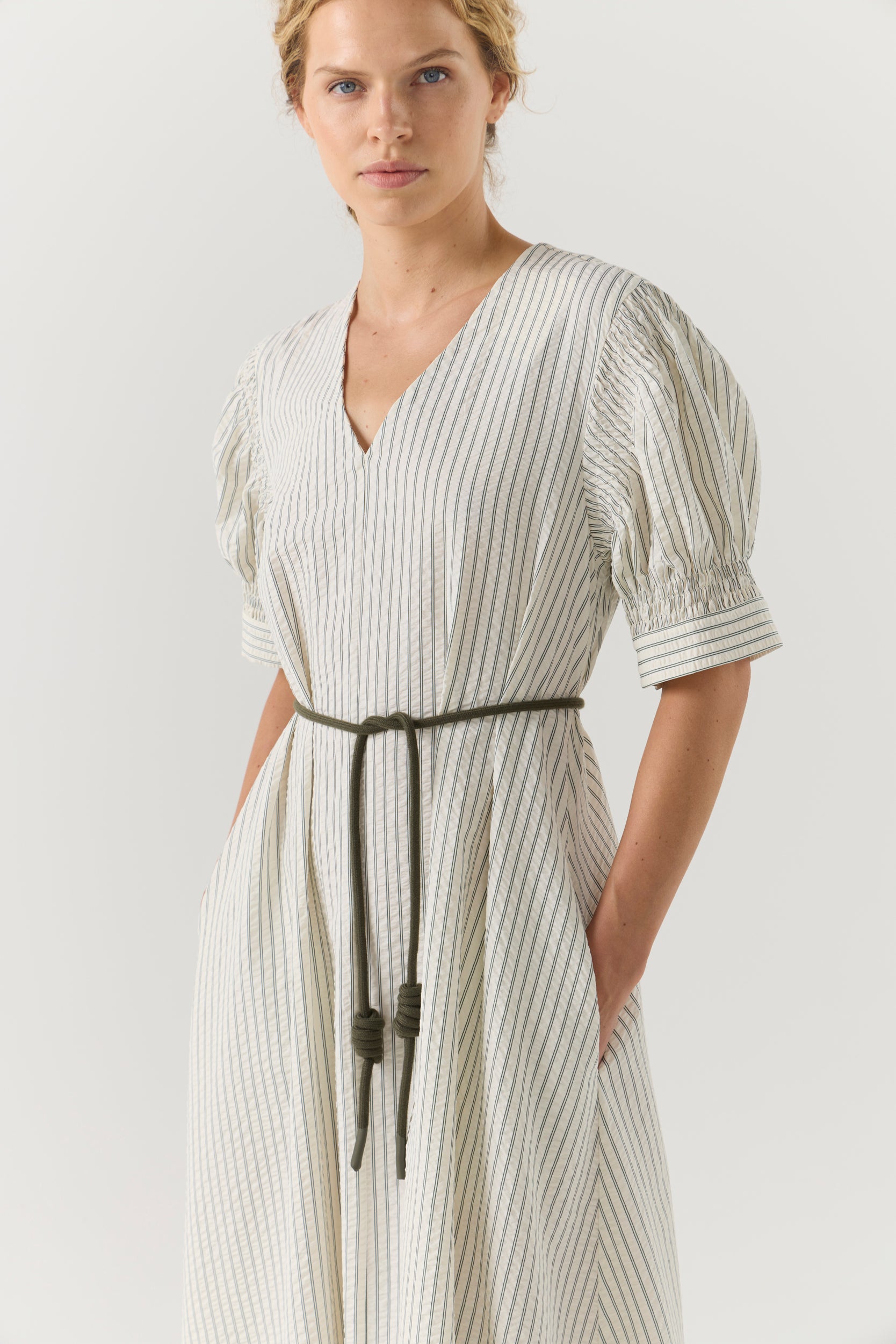 Woman wearing a white and green striped dress on a white background