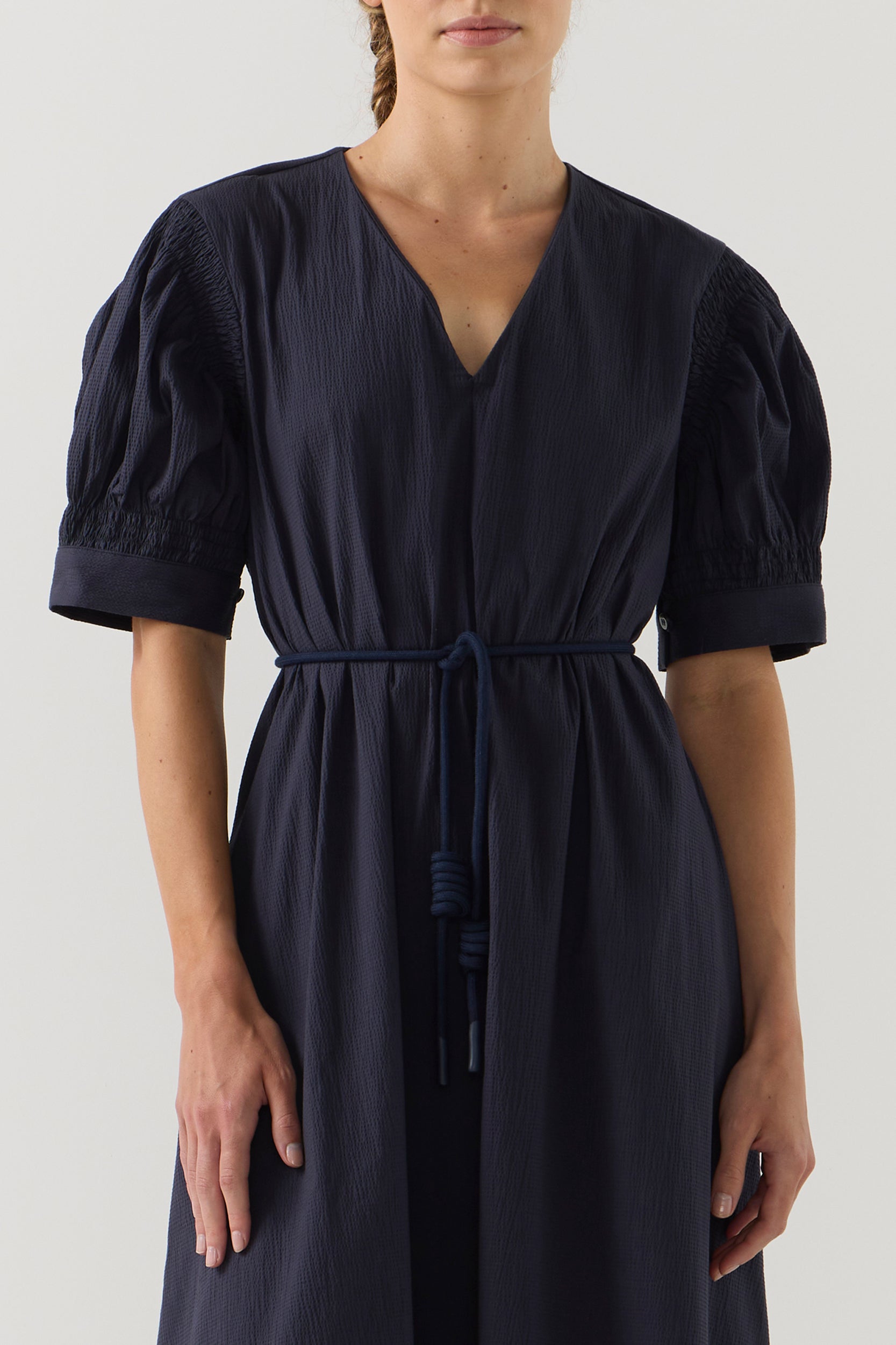 Woman wearing a dark blue dress with puff sleeves on a white background