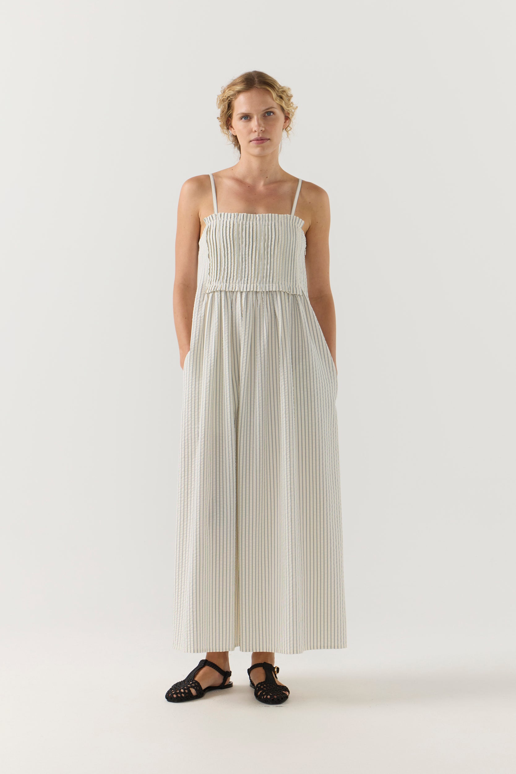 Woman wearing a white striped pleated dress on a white background
