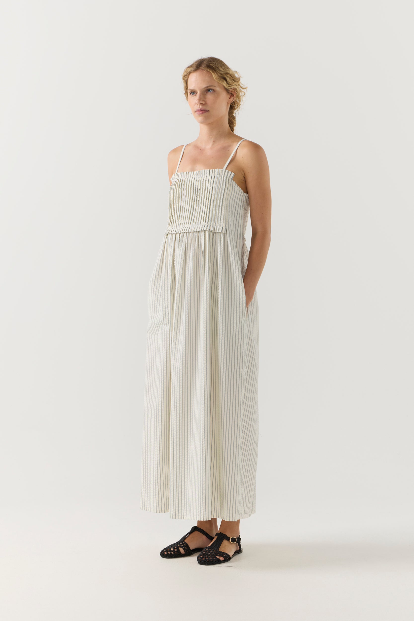 Woman wearing a white striped pleated dress on a white background