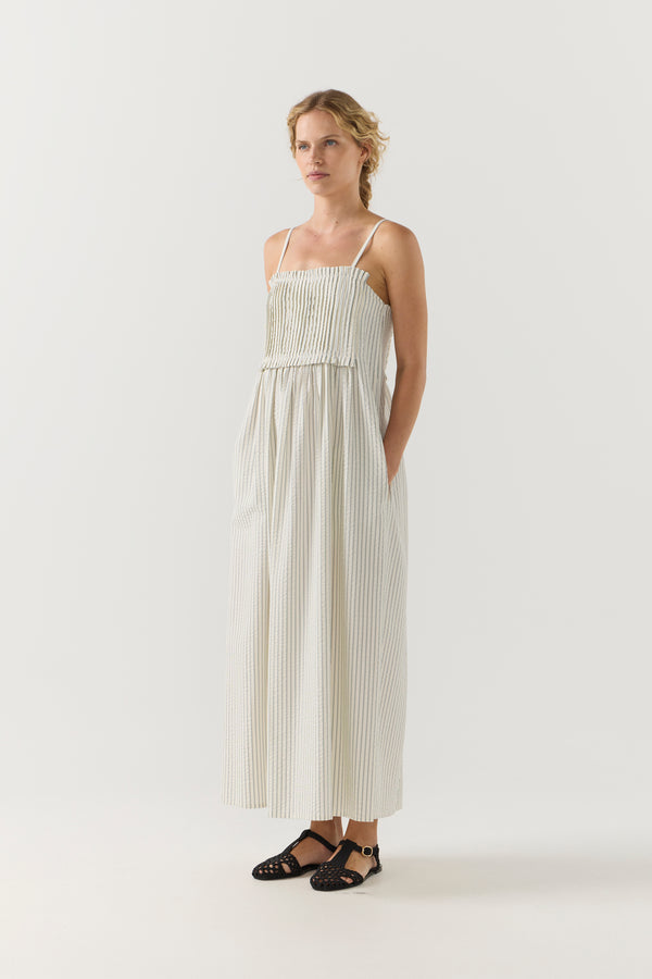 Woman wearing a white striped pleated dress on a white background