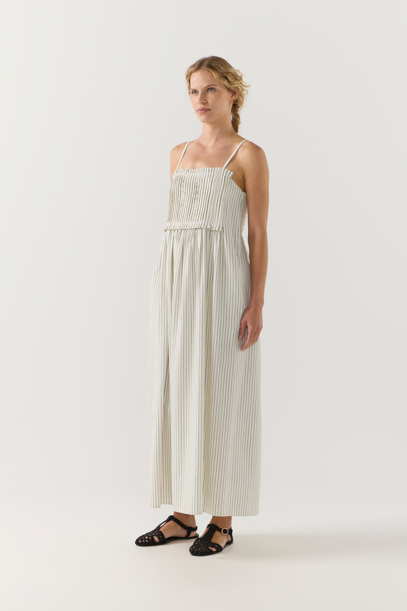 Woman wearing a white striped pleated dress on a white background