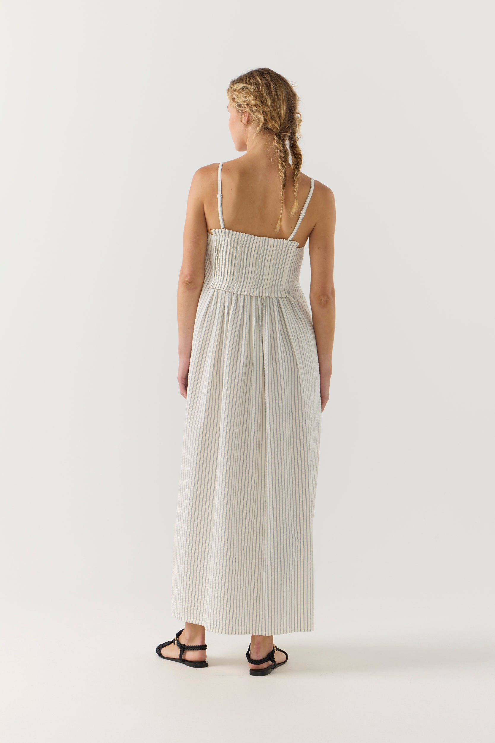 Woman wearing a white striped pleated dress on a white background
