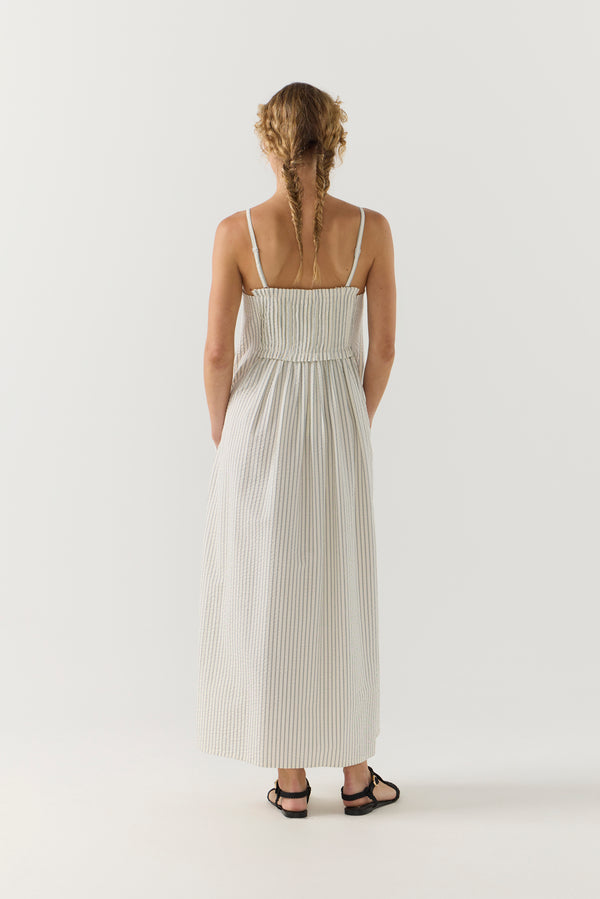 Woman wearing a white striped pleated dress on a white background