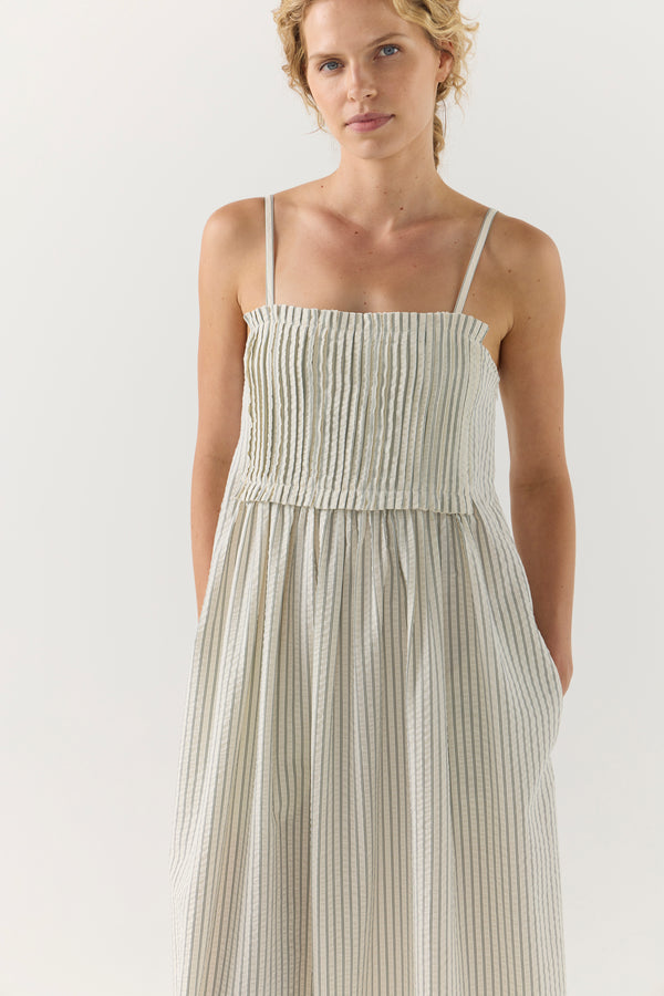 Woman wearing a white striped pleated dress on a white background