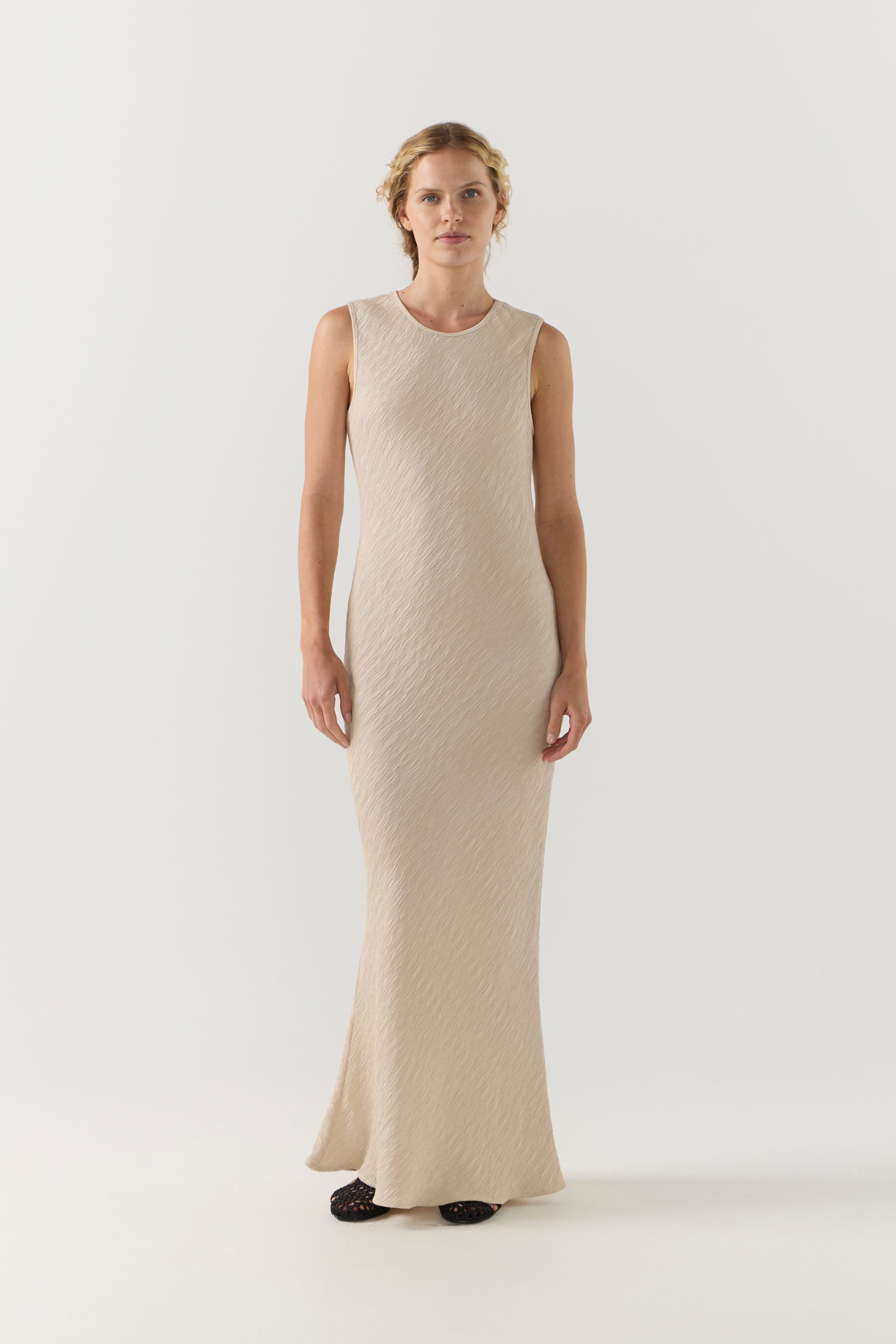 Woman wearing a beige sleeveless dress on a white background