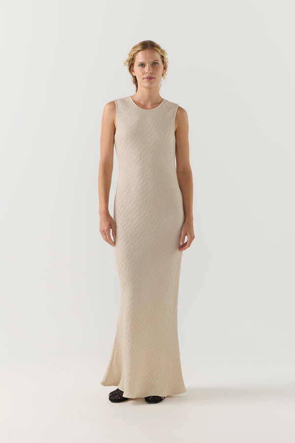 Woman wearing a beige sleeveless dress on a white background