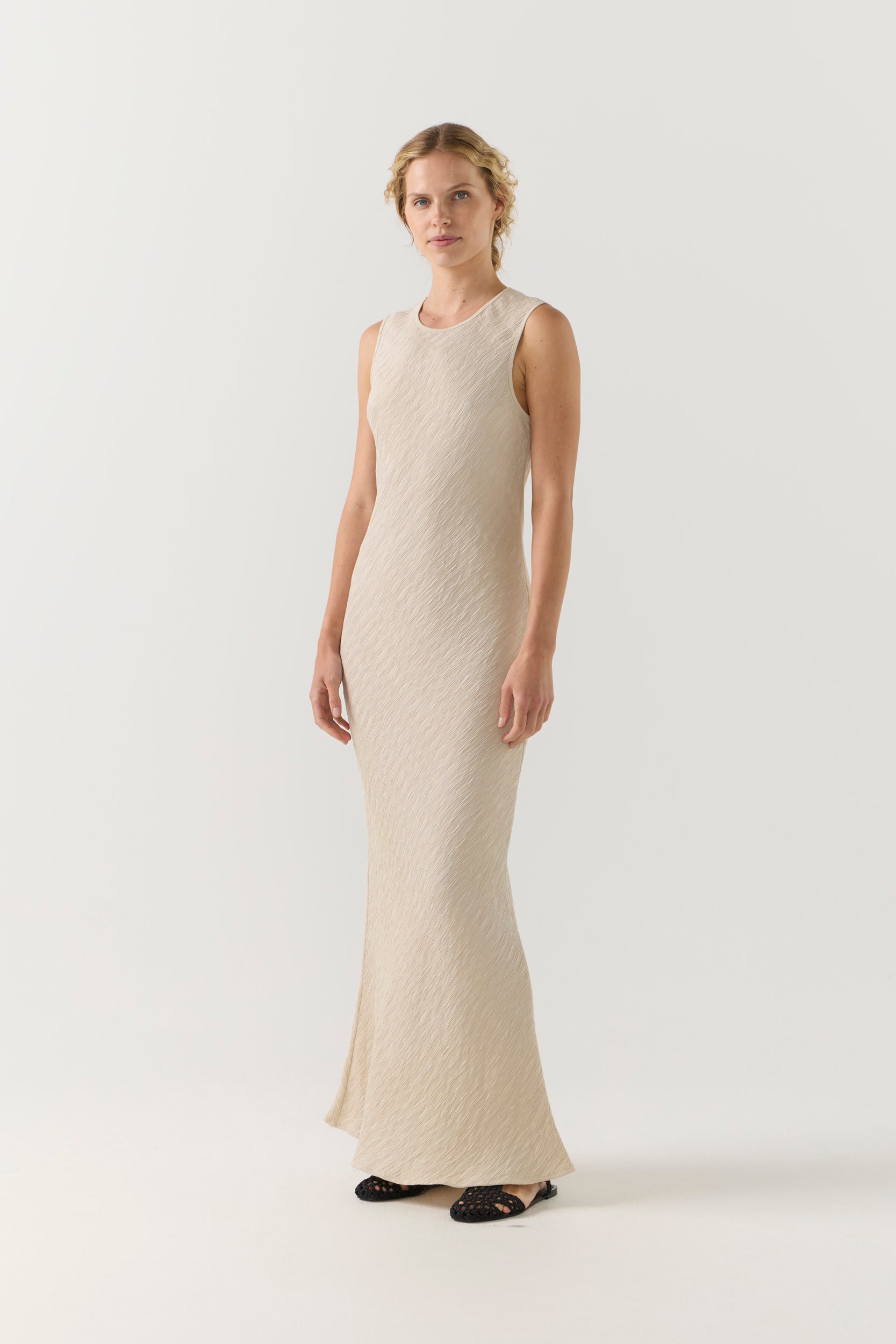 Woman wearing a beige sleeveless dress on a white background