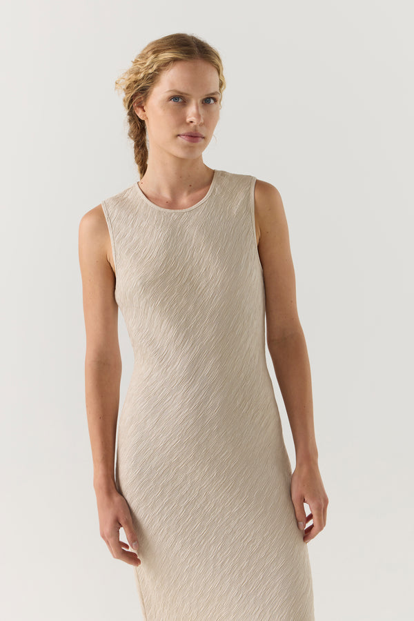 Woman wearing a beige sleeveless dress on a white background