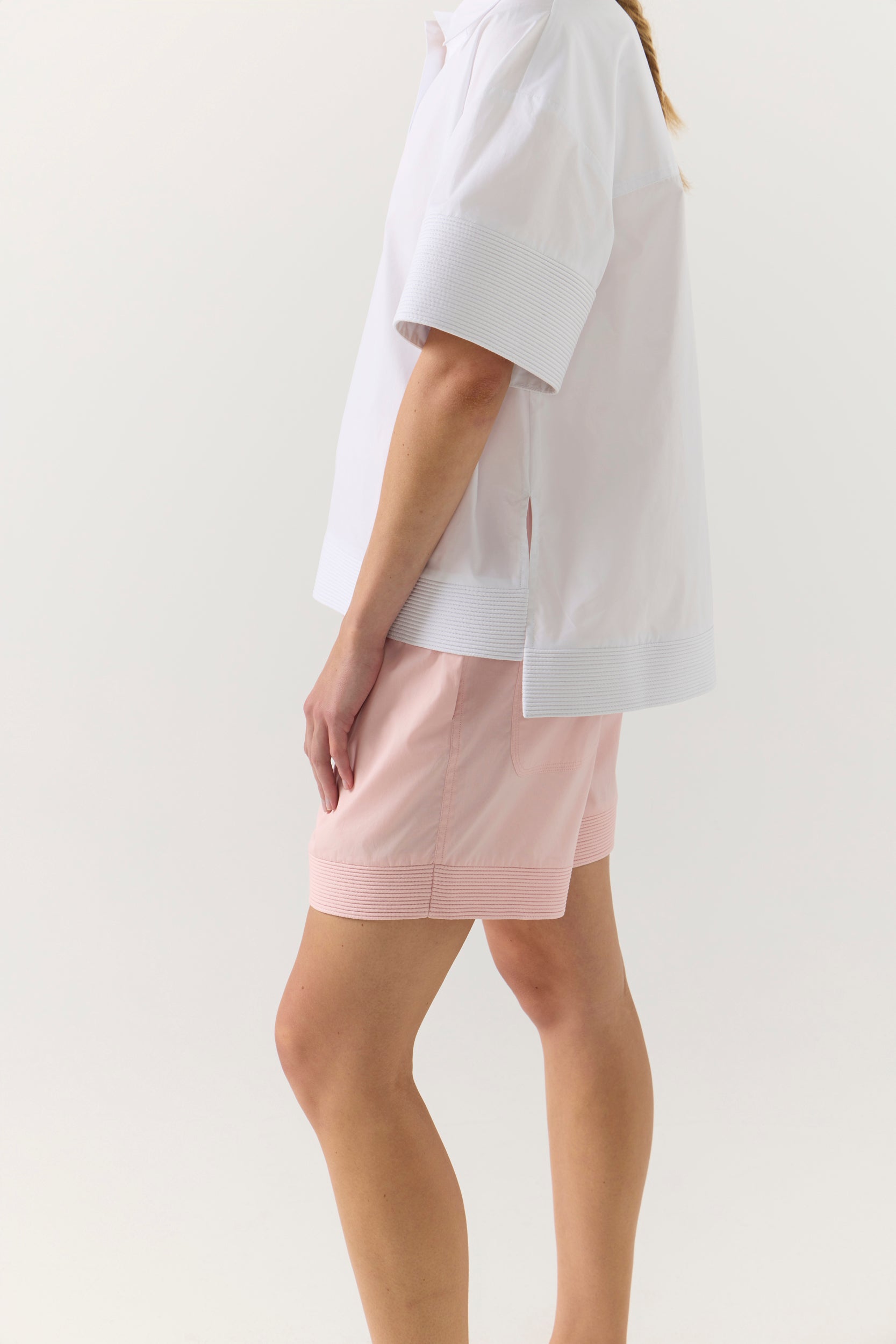 Woman wearing a white shirt and pink shorts on a white background